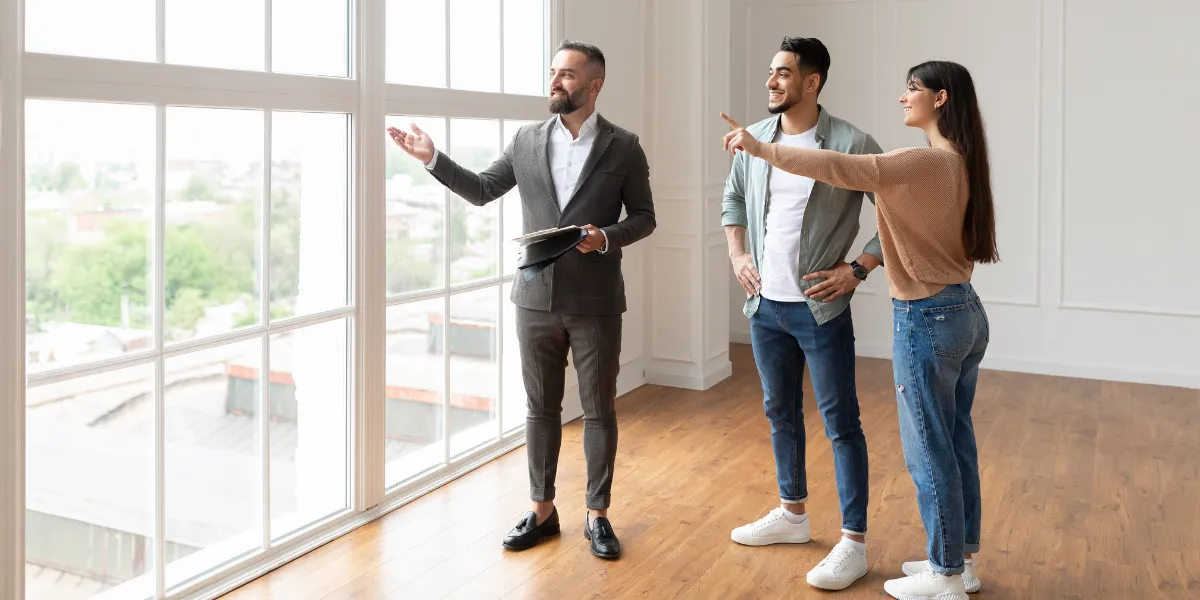 Agent immobilier faisant visiter une maison à vendre à un couple d'acheteur